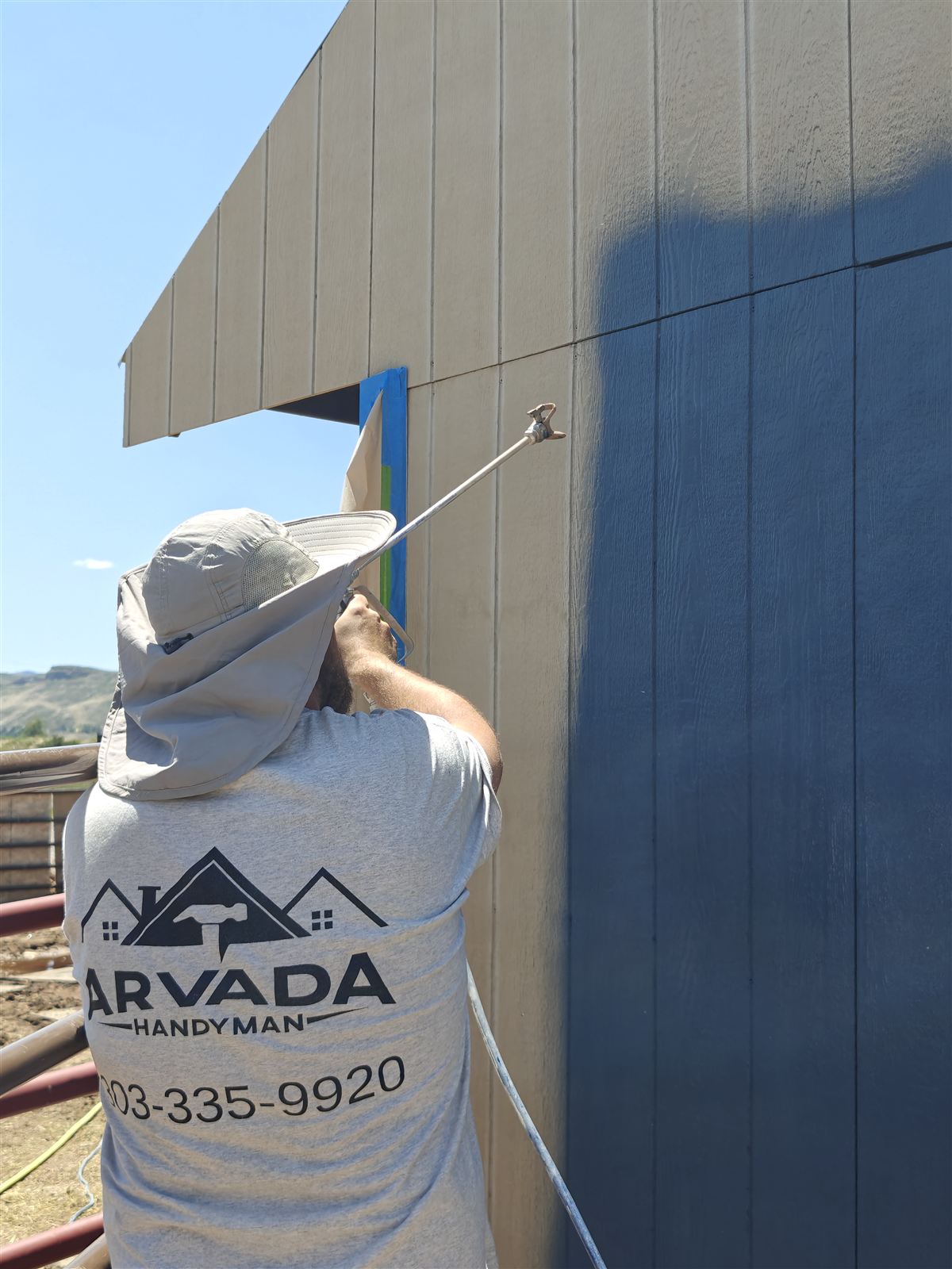 Close-up of the siding color transformation, tan primer coat next to freshly sprayed blue-gray finish