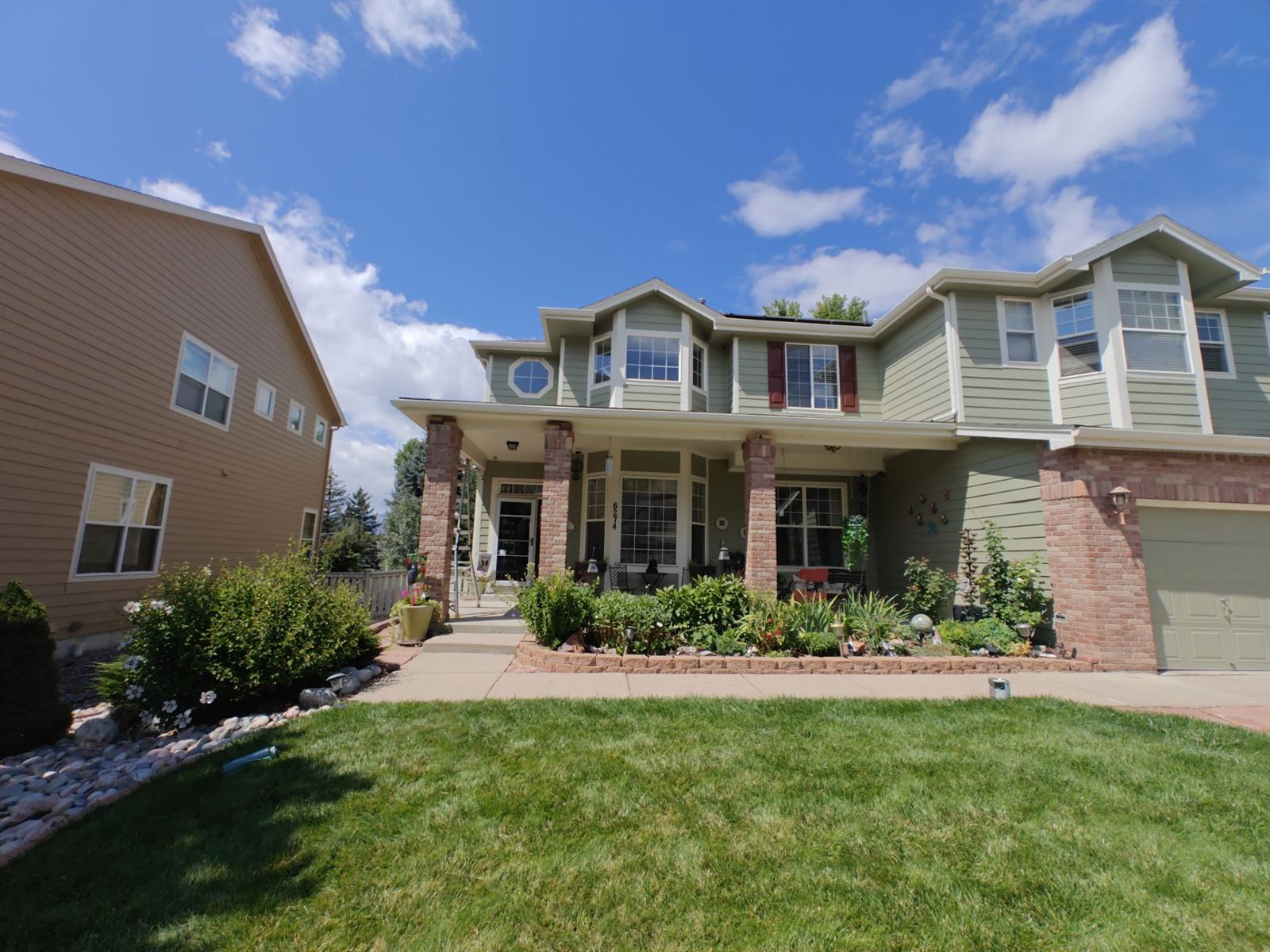 Completed two-tone exterior repaint of a two-story home in Arvada, Colorado, sage green siding with white trim