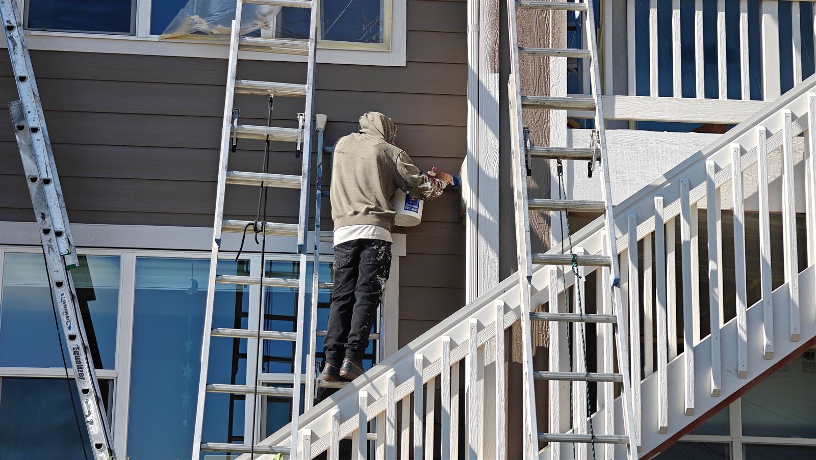 Exterior house painter applying finish coat to siding in Arvada, Colorado