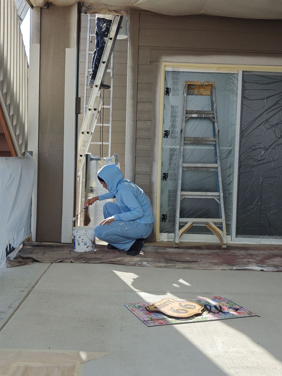 Painter masking and prepping windows and trim before an exterior paint job